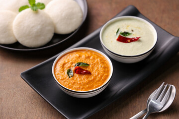 Many Idli or idly popular breakfast of Kerala South India and Sri Lanka. Healthy steamed rice cakes by steaming fermented batter of black lentils and rice coconut chutney tomato chutney.