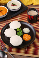 Many Idli or idly popular breakfast of Kerala South India and Sri Lanka. Healthy steamed rice cakes by steaming fermented batter of black lentils and rice coconut chutney tomato chutney.