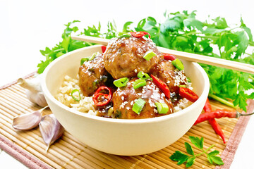 Meatballs in sweet and sour sauce with rice on light wooden board
