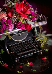 Still life - antique printing press and bright flowers on a dark background