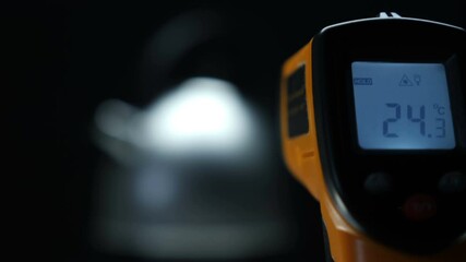 Measuring the temperature with a laser gun at a cold kettle and a boiling kettle. 100 degrees Celsius is the boiling point of water. Macro. Closeup