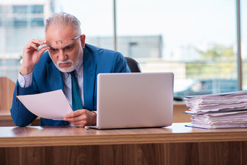 Fototapeta premium Old male employee working in the office