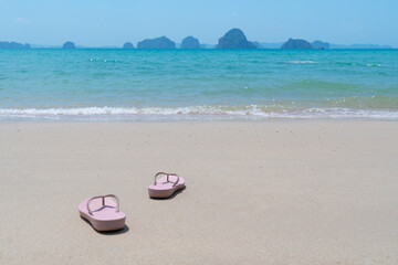 Fototapeta na wymiar pink beach walk slippers or sandles of young woman placing on white beach and blue sea on summer vacation. travel concept