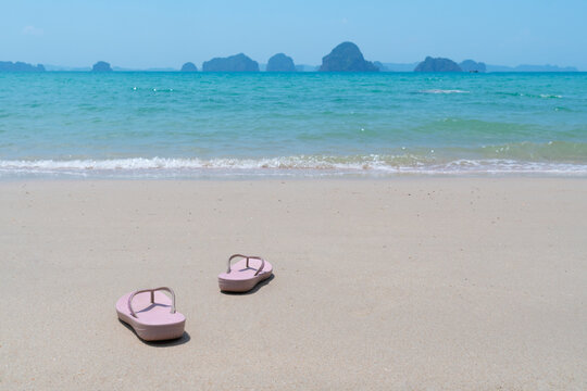 pink beach walk slippers or sandles of young woman placing on white beach and blue sea on summer vacation. travel concept