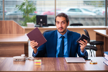 Young male employee reading book in the office