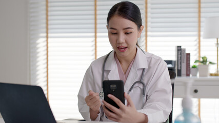 Obraz premium Attractive beautiful asia chinese female doctor video conference call online live talk follow up remotely in medical coronavirus result with patient at office. Online telehealth telemedicine service.