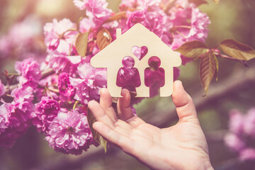 The girl holds the house symbol against the background of blossoming Sakura
