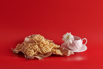 with a pink cup cookies on craft paper on a red background on a saucer 