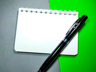 Selective focus of pen and notebook on gray and green background with copy space.