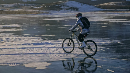 Woman is riding bicycle on the ice. Tires on bike are covered wi