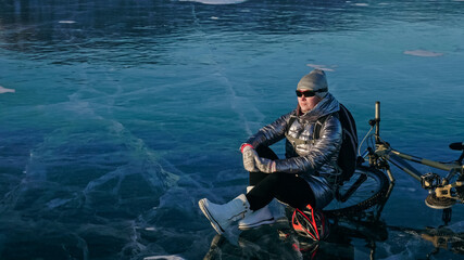 Woman sitting near her bike on ice. The girl cyclist stopped to