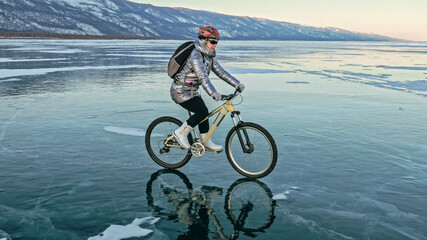 Fototapeta na wymiar Woman is riding bicycle on the ice. Tires on bike are covered wi