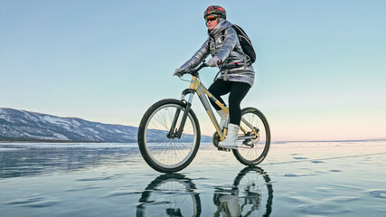 Obraz premium Woman is riding bicycle on the ice. Tires on bike are covered wi