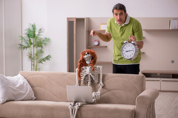 Young man with female skeleton in time management concept