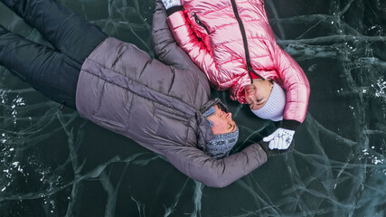 Couple has fun during winter walk against background of ice of f