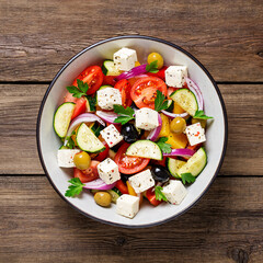 Classic Greek salad with fresh vegetables, feta cheese and olives. Healthy food. Wooden background. Top view	