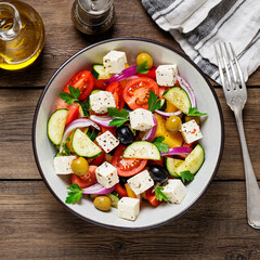 Classic Greek salad with fresh vegetables, feta cheese and olives. Healthy food. Wooden background. Top view	