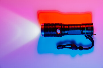 A small black flashlight in colored lighting. 