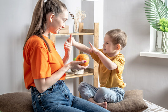 A happy mother in a playful way is teaching her little son to count using fruits. Concept of family, pastime and activities with the child