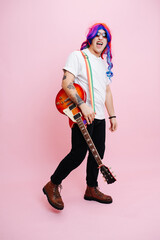 Silly rock musician posing with his instrument. Over pink background