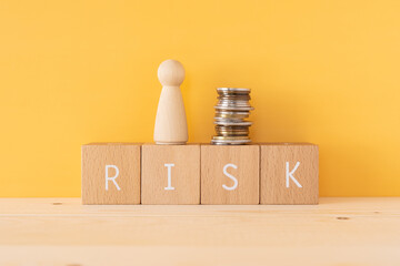 リスク｜「RISK」と書かれた積み木と人型オブジェとお金
