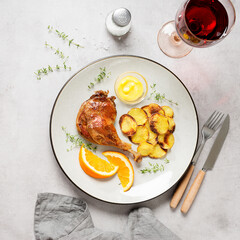 Duck leg confit served with potato chips and mustard sauce .Traditional french cuisine. Light gray background, top view. 