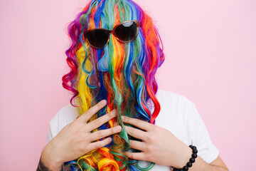 Extremely funny looking man in a wig over face and sunglasses over pink - obrazy, fototapety, plakaty