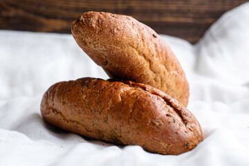 two freshly baked rye bread rolls on a white cloth napkin