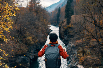 woman tourist stands on the bridge over the river or admires the nature landscape