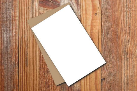 Blank paper sheets and brown envelope for brochure on wooden background in top view Mock up