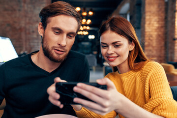 young couple man and woman in a restaurant ordering food and mobile phone in hand lighting