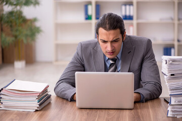 Young male employee unhappy with excessive work in the office