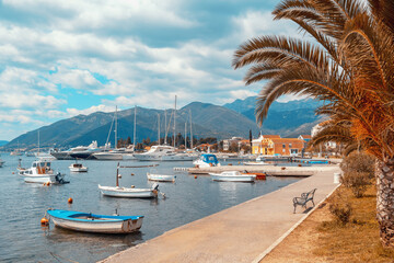 Fototapeta na wymiar Beautiful Mediterranean landscape with village embankment and fishing boats on water. Montenegro, Adriatic Sea, view of Bay of Kotor and Seljanovo village near Tivat city. Color toning