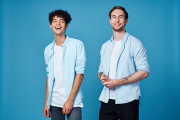 guys in identical shirts and a t-shirt on a blue background friends gesticulate with their hands