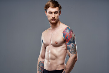 Fototapeta premium sporty man with pumped up press tattoo on his arms macho cropped view
