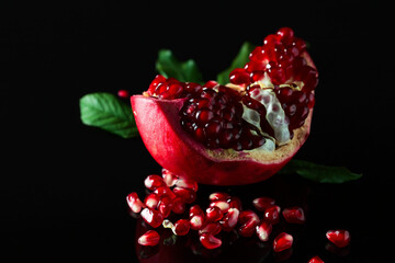 Broken pomegranate on a black reflective background.