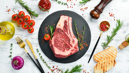 Grilled beef ribeye steak on the bone on a white wooden background. Flat lay. Top view.