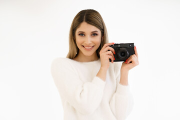 Beautiful Hipster woman taking photos with black retro film camera on white background. Close up. Indoor. Warm color. Blogger