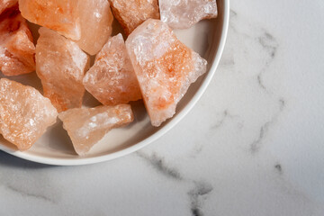 Organic Himalayan mineral salt crystals on round ceramic tray. Interior decoration and spa ingredient for wellness procedures