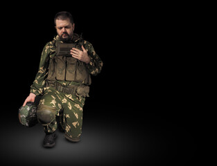 Military man praying on black background