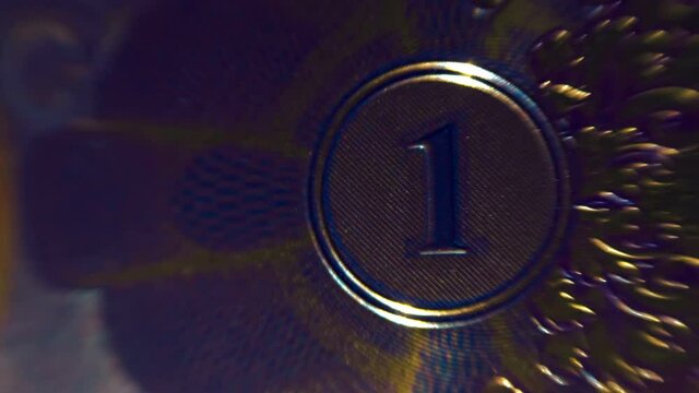 Digit 1 in a patterned embossed glitters in a beam of light. It can be used as number one, as one monetary unit, in document circulation, in this case it symbolizes 1 bitcoin. Macro. Closeup