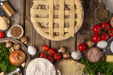 Cooking pie with mushrooms and meat top view with ingredients on a wooden table. Flat lay