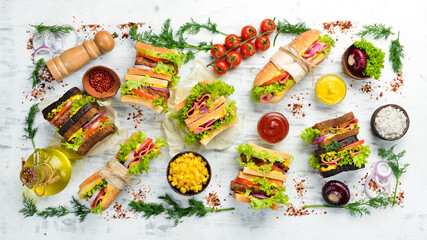 Sandwiches and burgers on a white wooden background. Top view. Street food.