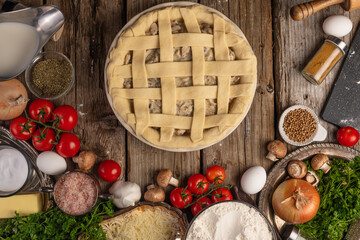 Cooking pie with mushrooms and meat top view with ingredients on a wooden table. Flat lay