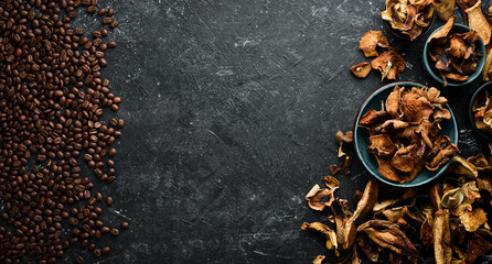 Fragrant coffee beans and dried mushrooms on a black stone background. Organic food, superfood. Top view. Free space for text.