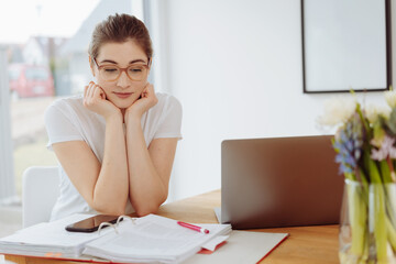Obraz premium Thoughtful young woman sitting staring down at her notes in a binder