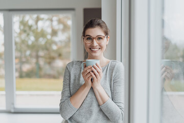 Fototapeta na wymiar Cute charismatic happy young woman enjoying a mug of coffee