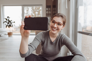 Happy young woman posing for a selfie on her mobile phone