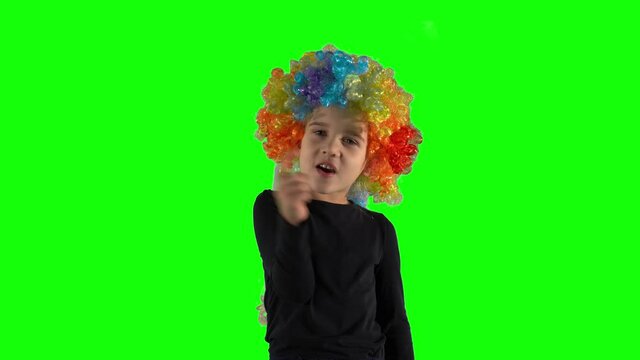 Preschooler child in colorful wig showing no no no gesture with finger