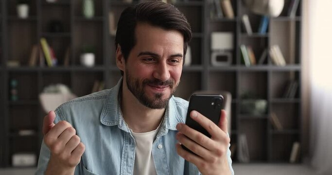 Happy young handsome caucasian man looking at smartphone screen, holding web camera video call zoom conversation with friends or family, talking speaking chatting communicating distantly indoors.